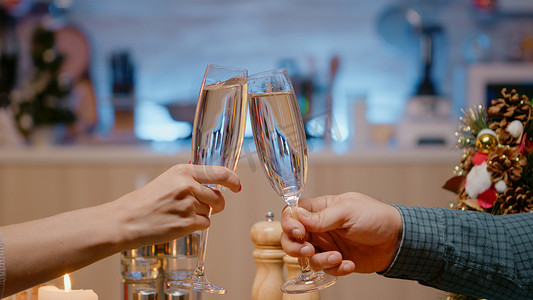 一对夫妇在节日晚餐上的特写，他们碰杯香槟