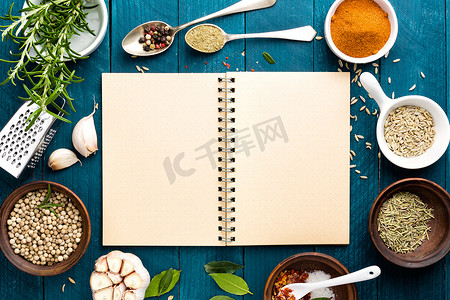 食物香料摄影照片_烹饪背景和木桌上有各种香料的食谱书