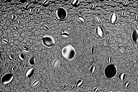 白色发光体摄影照片_黑色和白色的油滴在水面上。