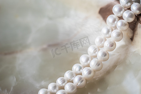 大理石背景上的天然白色珍珠串，焦点柔和，有亮点