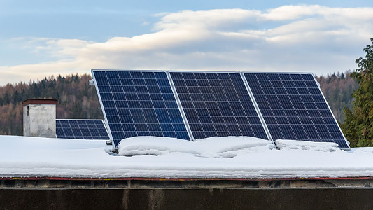 冬天屋摄影照片_积雪屋顶上的太阳能电池板