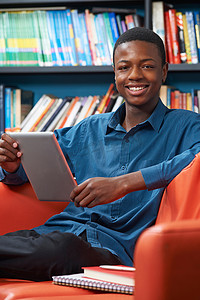 男性青少年学生在图书馆使用数字平板电脑