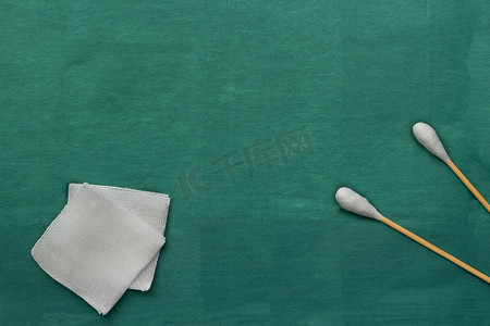 纱布白色摄影照片_绿色医用手术服上的纱布和棉签棉巴士棒