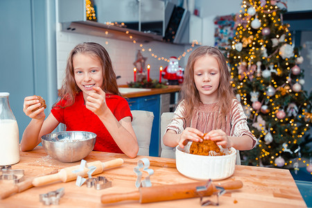 小女孩在装饰精美的客厅的壁炉旁制作圣诞姜饼屋。