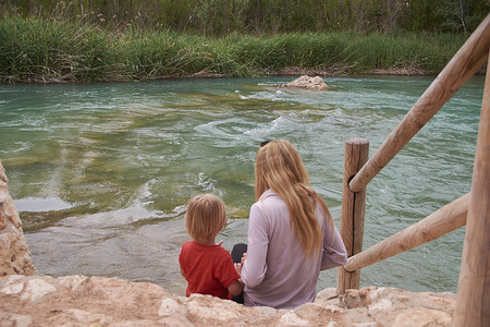 母子俩看着波涛汹涌的河流，