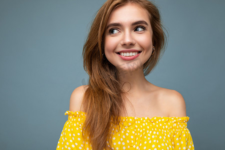 年轻迷人的微笑金发女人的特写照片与真挚的情感隔离在背景墙上，复制空间穿着时尚的夏季黄色连衣裙。