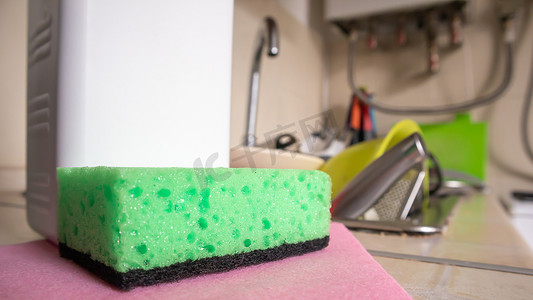绿色海绵和液体肥皂分配器，用于完全用碗碟和厨房用具在脏水槽上洗碗。