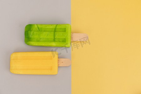 灰色和黄色背景上的冰淇淋棒。