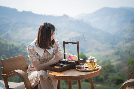 坐在椅子山景上吃蛋糕喝热绿茶的美女