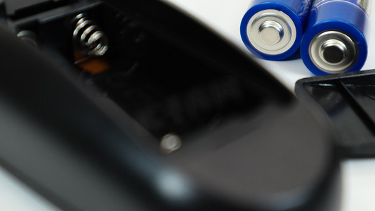 加减号白色摄影照片_有蓝色 AAA 电池的黑色遥控器在白色背景。