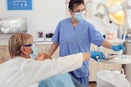 牙齿预防摄影照片_在牙科手术中工作的医院团队分析牙齿健康