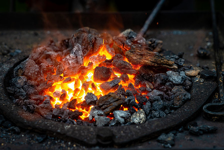 红色的舌头摄影照片_热的物品被插入铁匠的熔炉中，从那里发出火焰的舌头。