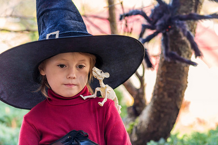 万圣节派对上，穿着女巫服装的小女孩拿着骷髅