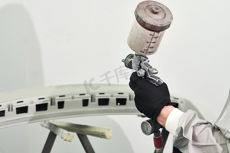 修理车摄影照片_维修汽车服务中喷漆室喷漆车的机械喷漆保险杠