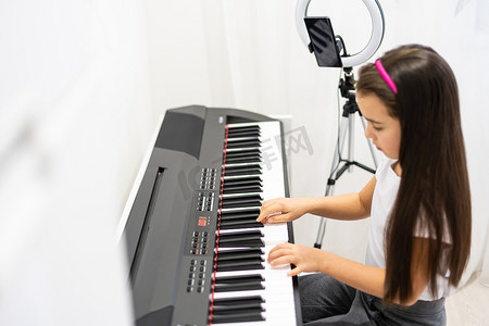 儿童女孩演奏音乐键盘钢琴乐器并拍摄视频