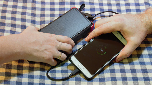 充电宝充电摄影照片_用别人的太阳能充电宝和数据线给手机充电