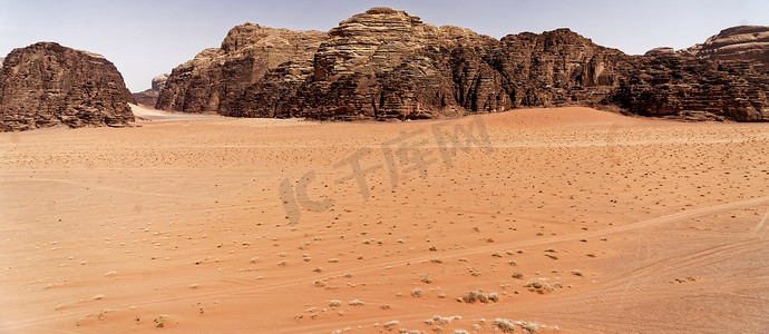 瓦迪拉姆 (Wadi Rum) 自然保护区大沙漠的空旷，背景是大片红砂岩山脉，俯瞰广阔的沙质平原。