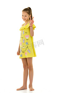 黄色手指手势摄影照片_穿着黄色棉质连衣裙的微笑少女展示胜利手势