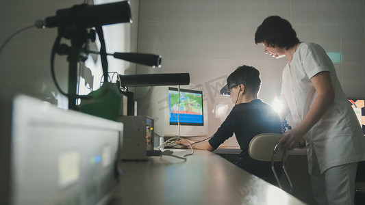 立体医学摄影照片_女医生借助立体视频虚拟现实眼镜检查孩子的视力
