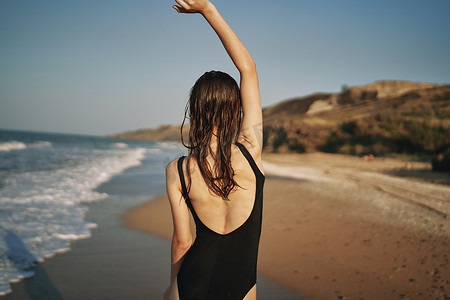 夏天散步摄影照片_女人穿着黑色泳衣太阳热带沿着沙滩散步