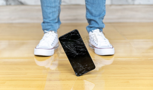 人们将智能手机掉在地板上破碎的屏幕