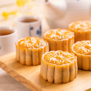 中中秋节摄影照片_明亮的木桌上有茶的月饼和服务尝试，中秋节传统食品布局设计的节日概念，特写，复制空间。
