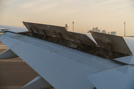 襟翼摄影照片_从乘客窗口看 — 日落时飞机机翼在跑道上方高速着陆，襟翼升起