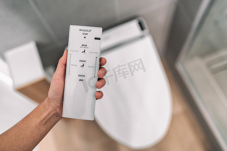 洗马桶摄影照片_带遥控器的智能日式坐浴盆自动坐便器，无需使用卫生纸即可轻松用水冲洗。