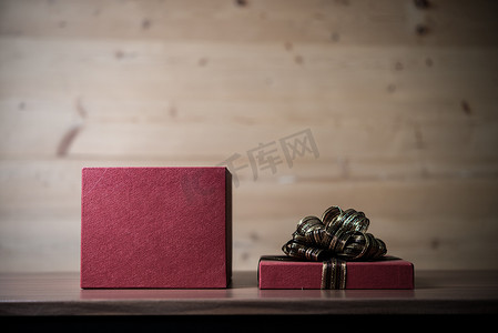 红色缎带摄影照片_木制的桌子上的红色缎带的圣诞礼物。