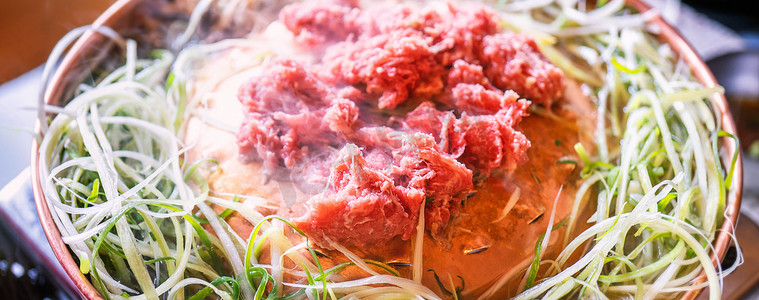 韩国烤肉摄影照片_首尔韩国餐厅的牛肉烧烤烤肉，铜锅上的生活方式新鲜韩国美食，带切片烤架，特写，复制空间