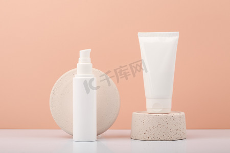 在米色背景下的白色桌子上，带有擦洗和面罩的白色管子，用于面部或手部皮肤。