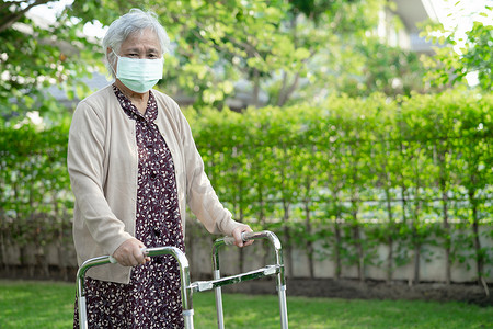 亚洲老年或老年老妇人带着助行器走路，戴着面罩以保护安全感染 Covid-19 Coronavirus。