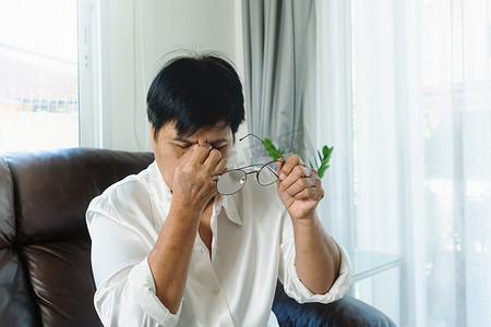 看完摄影照片_疲惫的老妇人看完纸质书后摘下眼镜，按摩眼睛。