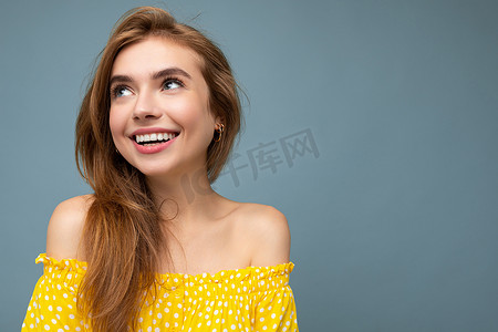 夏季衣服可爱摄影照片_特写照片的年轻令人愉快的微笑美丽的深色金发女人与真诚的情感隔离在背景墙上与复制空间穿着时尚的夏季黄色连衣裙。