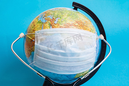 医疗防护面罩中的地球仪和蓝色背景中的听诊器