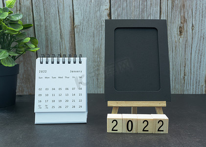 日历绿色摄影照片_2022 年 1 月带黑色记事本和木块的白色日历