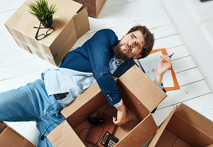 一个拿着箱子的男人躺在办公室搬家的地板上拆包