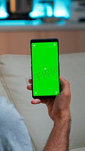 看着带模拟绿屏色度键显示的智能手机的轻松男人