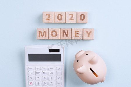 几何蓝摄影照片_摘要 2020 年财务目标设计概念 — 蓝桌背景上的几何木块立方体，带有存钱罐、顶视图、平躺、复制空间。