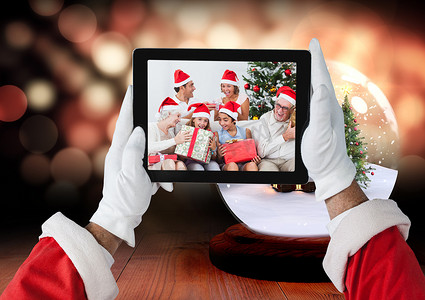 圣诞老人拿着带有圣诞节家庭照片的数字平板电脑