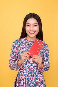 红包钱摄影照片_黄色背景中带着红包的漂亮微笑的越南女人