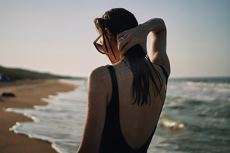 穿着黑色泳衣的女人在沙滩海洋夏日散步