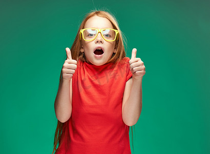 情绪激动的红发女孩,戴着黄色眼镜,红色 t 恤,情绪工作室,绿色背景
