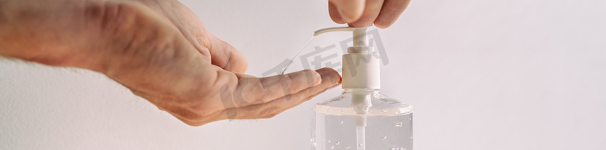 消毒凝胶摄影照片_COVID-19洗手液瓶男使用带消毒凝胶横幅的卫生清洁手