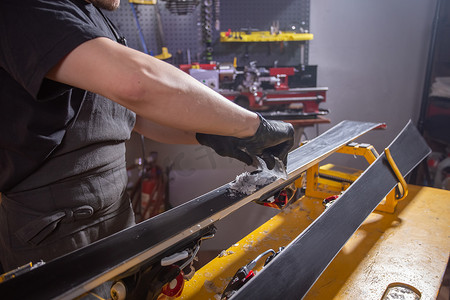 工作和修理概念 — 男人的手通过摩擦石蜡修理滑雪板