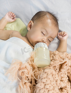 奶可爱摄影照片_宝宝喝奶瓶里的奶，睡在床上