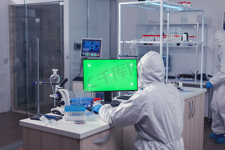 坐在工作场所的科学家使用带绿屏的电脑