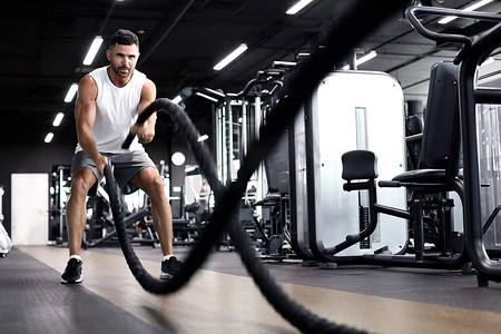 怀旧运动会摄影照片_运动年轻人带着战绳在功能训练健身馆锻炼。