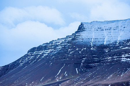 冰岛白雪覆盖的黑色山脊，云层增加了深度。