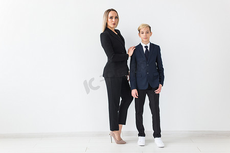 年轻的商人摄影照片_青少年和单亲家长-年轻的母亲和儿子站在白色背景上。
